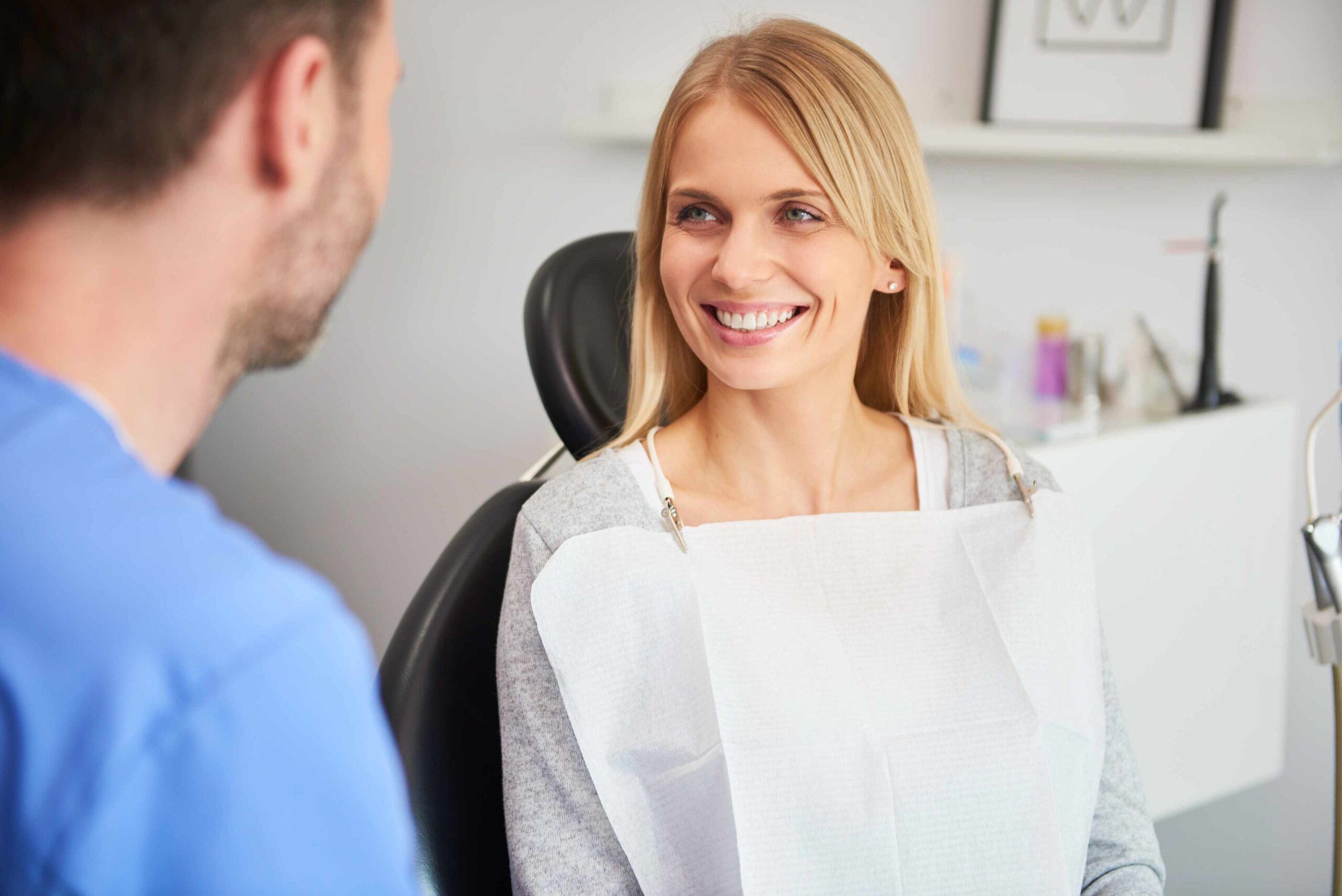 Patient smiling while discussing cosmetic dental treatment options with dentist in office.